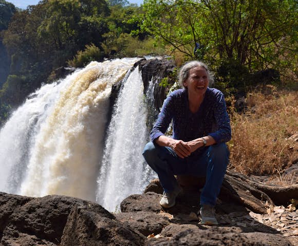 Woman sitting and smiling in front of Blue Nile Falls