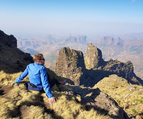 Man sitting on ledge admiring the landscape in the Simien Mountains