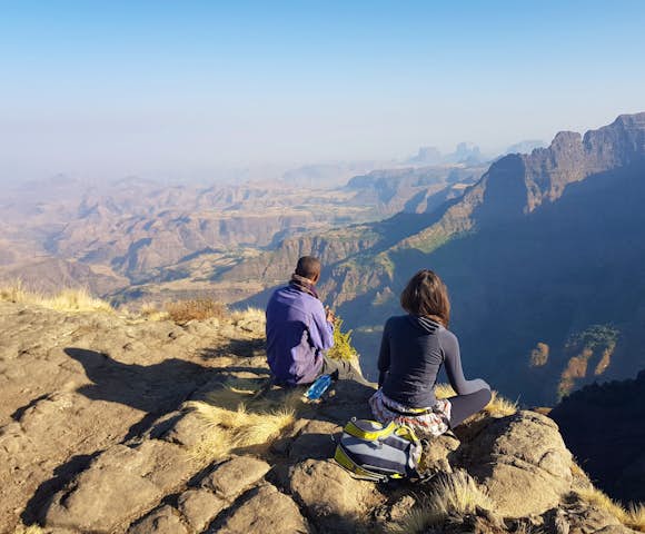Two people sitting on cliff edge looking at the view in the Simien Mountains